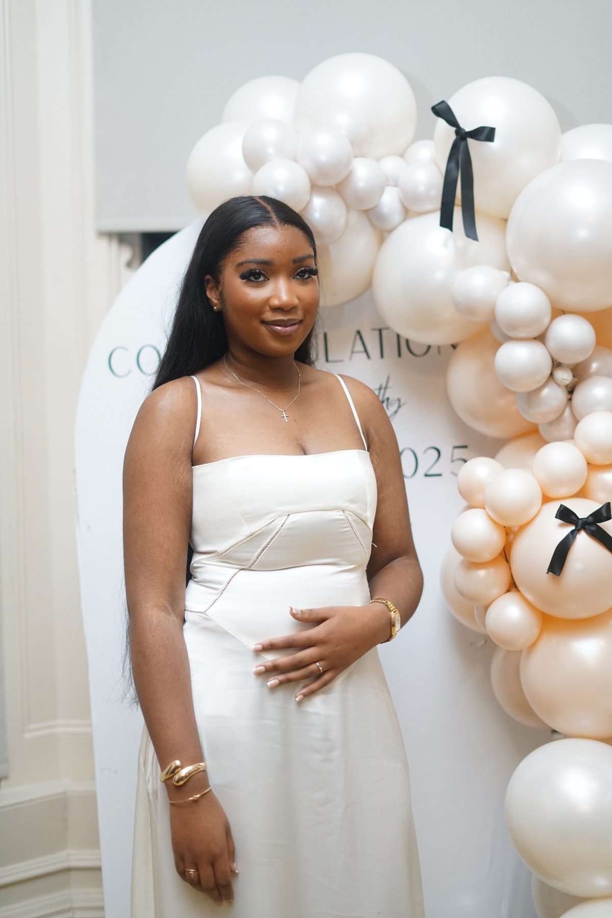 Graduate beside a pearl balloon garland with black bows