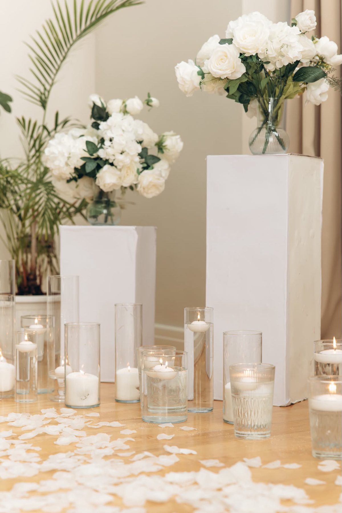 White roses, candles and petals arranged on plinths
