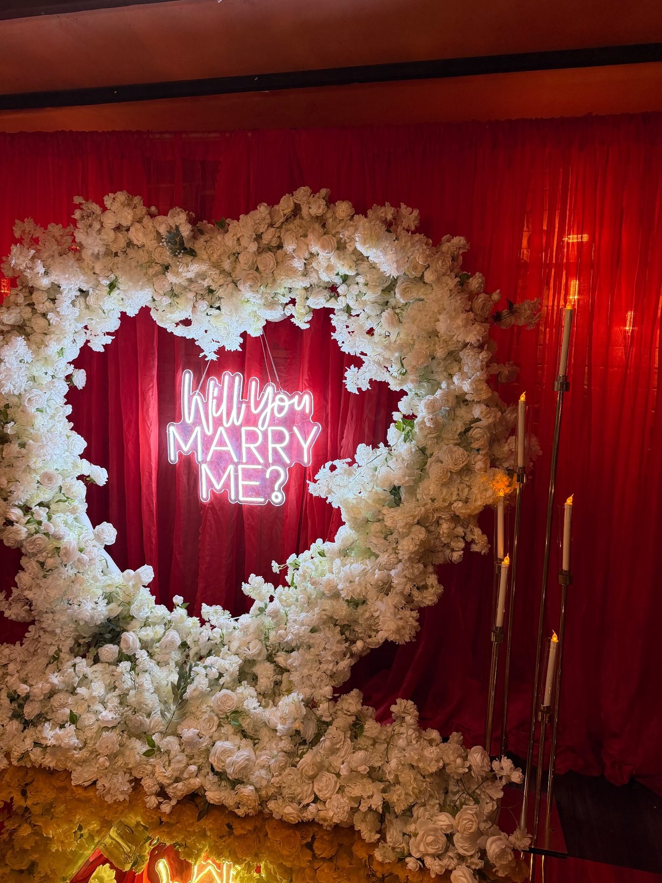 Proposal heart of white flowers framed by red curtains