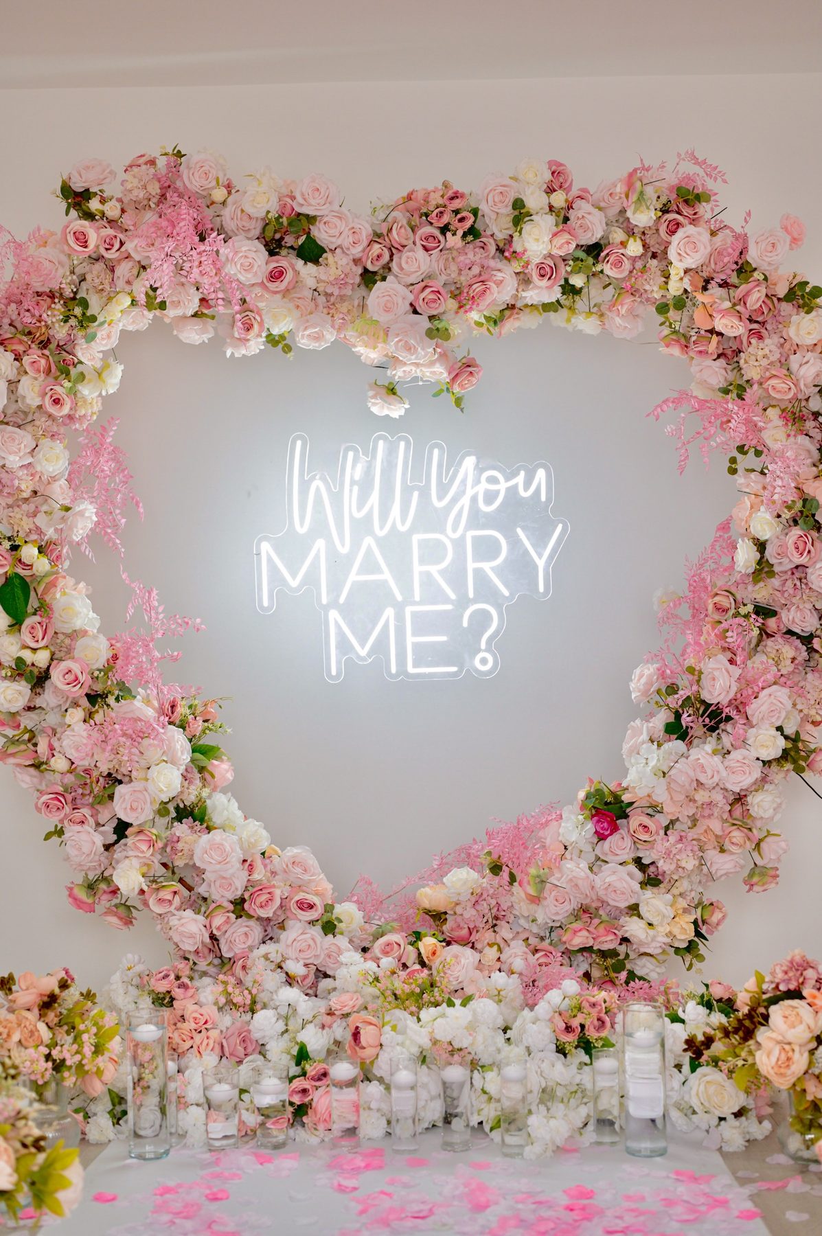 Pink floral heart arch with a Will You Marry Me neon sign
