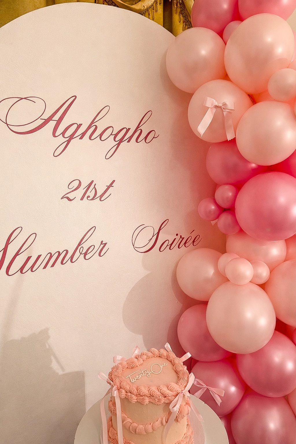 Close detail of a script lettered arch with pink balloons